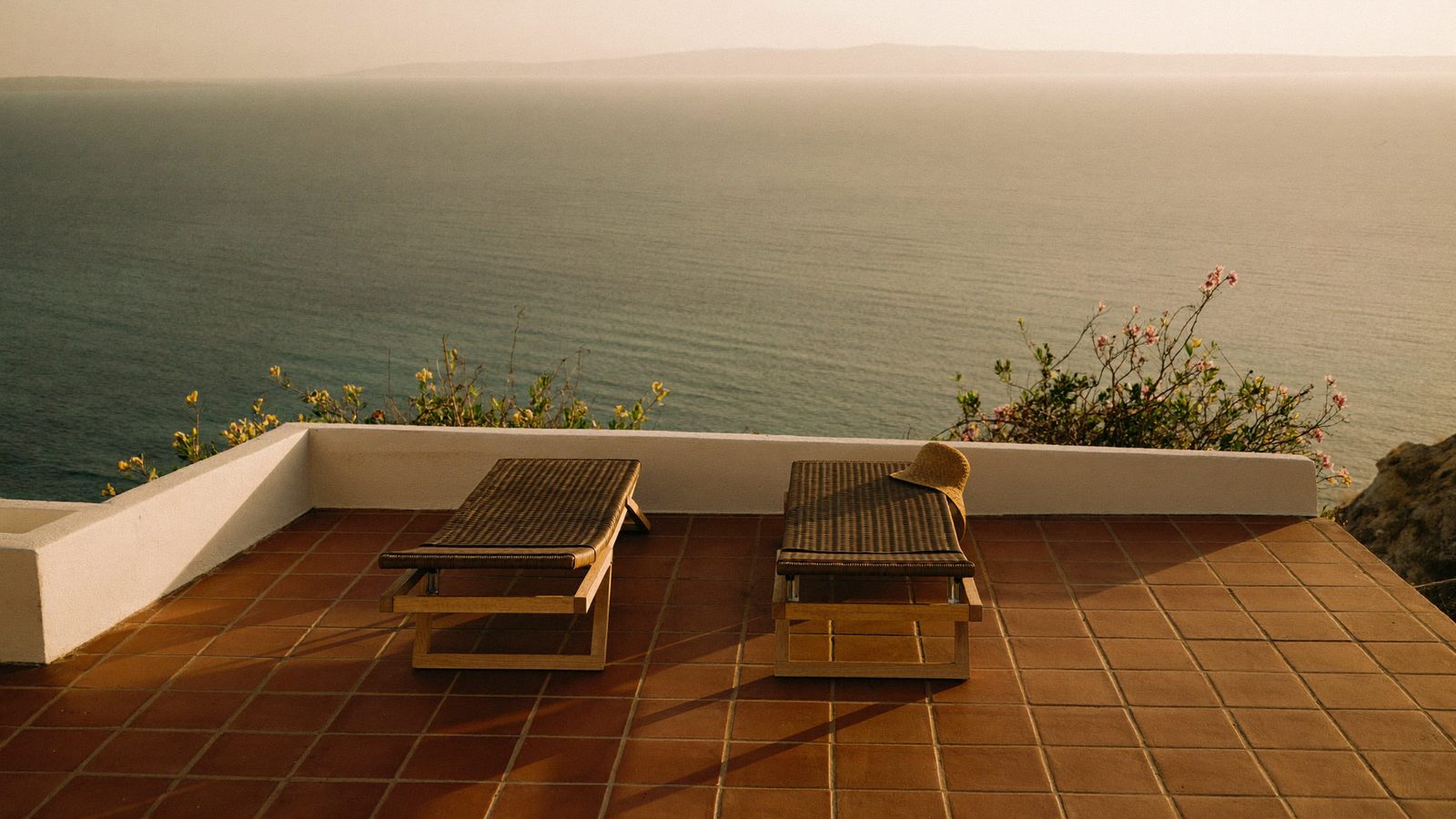 Sun loungers on a whitewashed Spanish terrace above the Mediterranean at golden hour — the retirement the State Pension rules decide